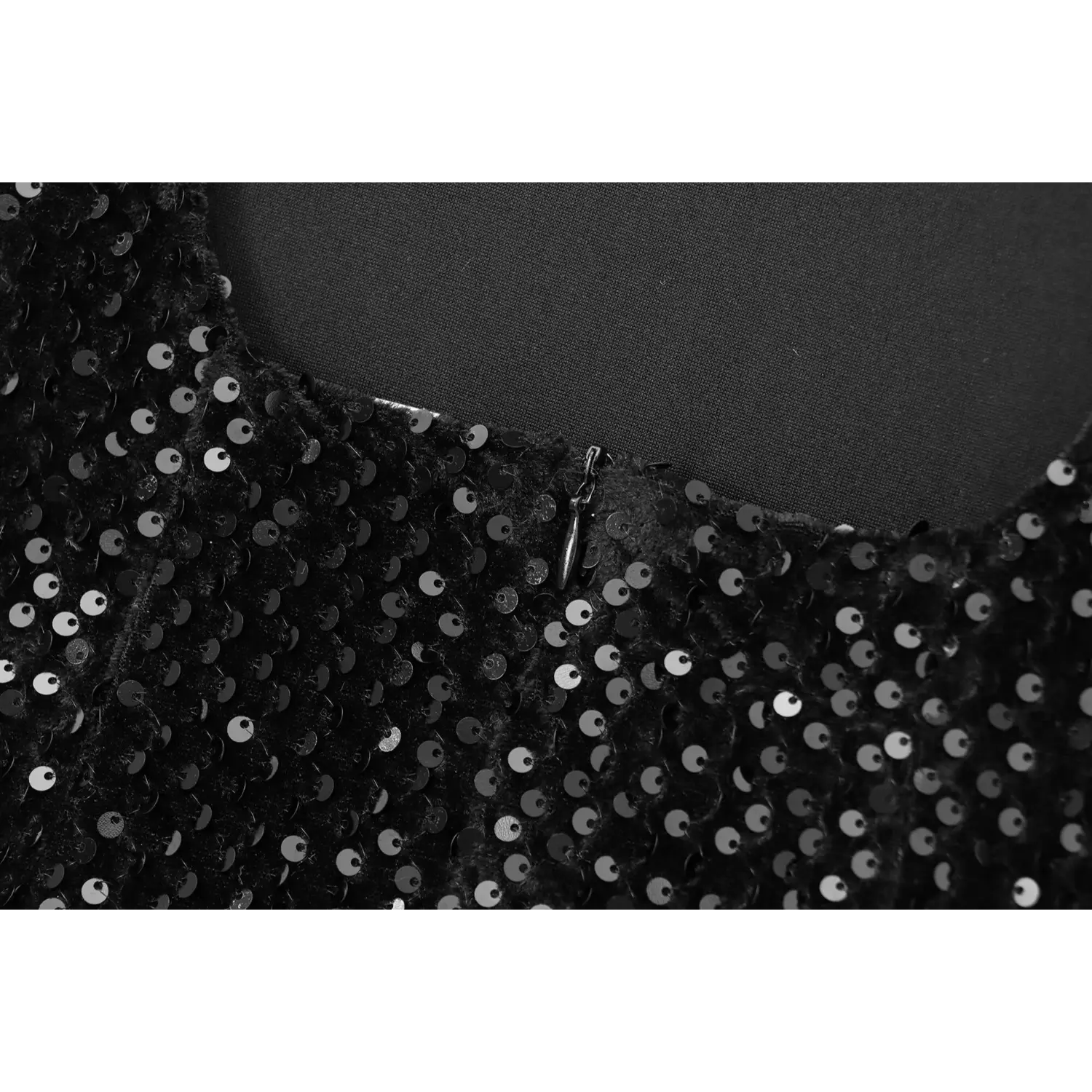 Close-up of the zipper pull tab on the back of black sequin party dress