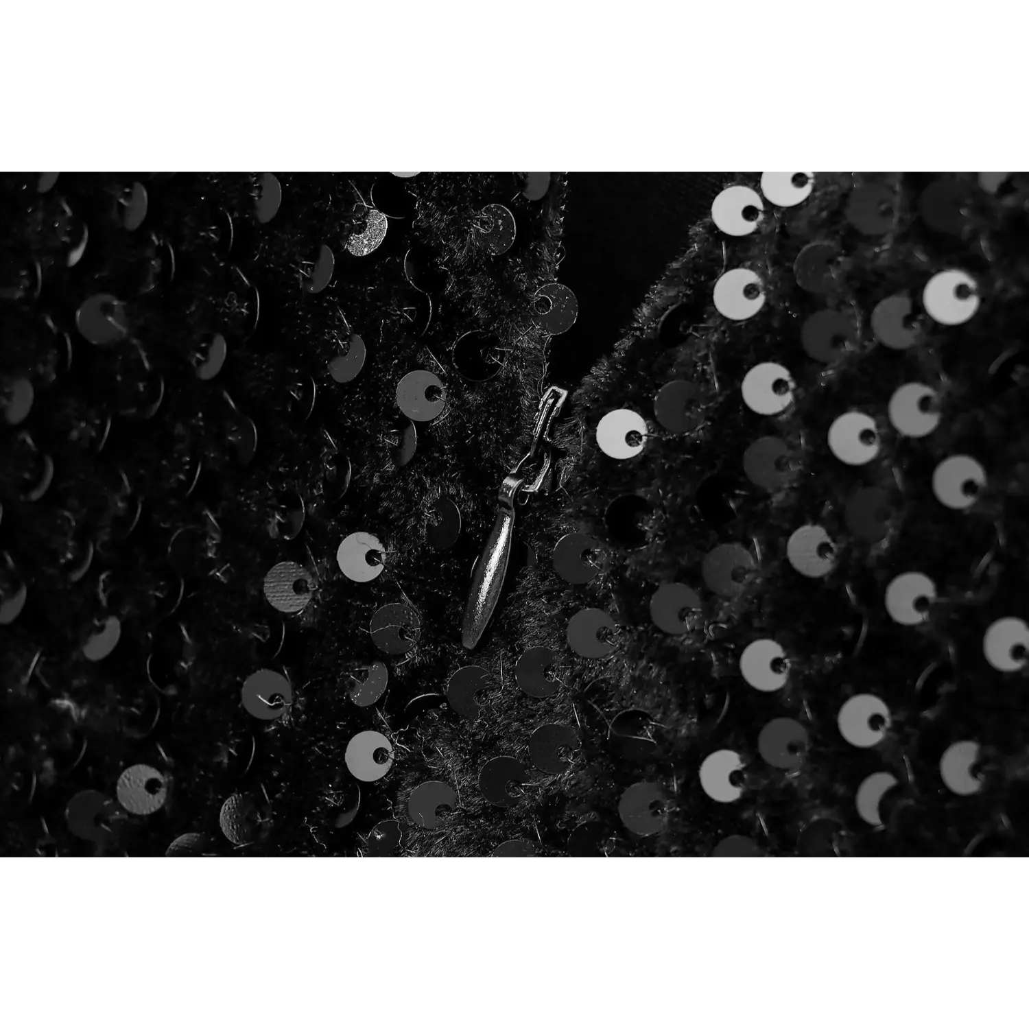 Close-up of the back zipper pull tab on black sequin party dress