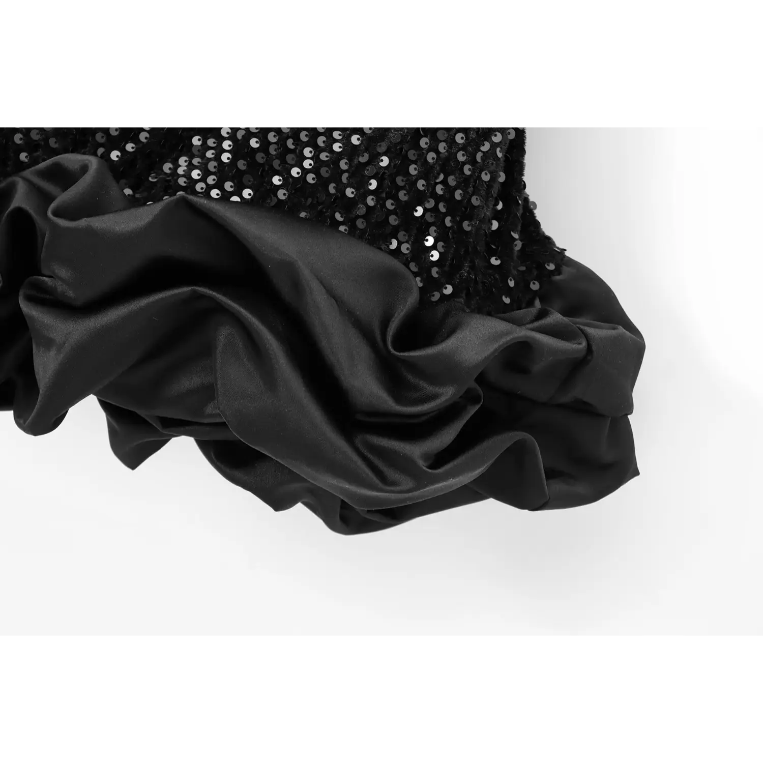 Close-up of the satin ruffled hem on black sequin party dress, showing the layered fabric texture