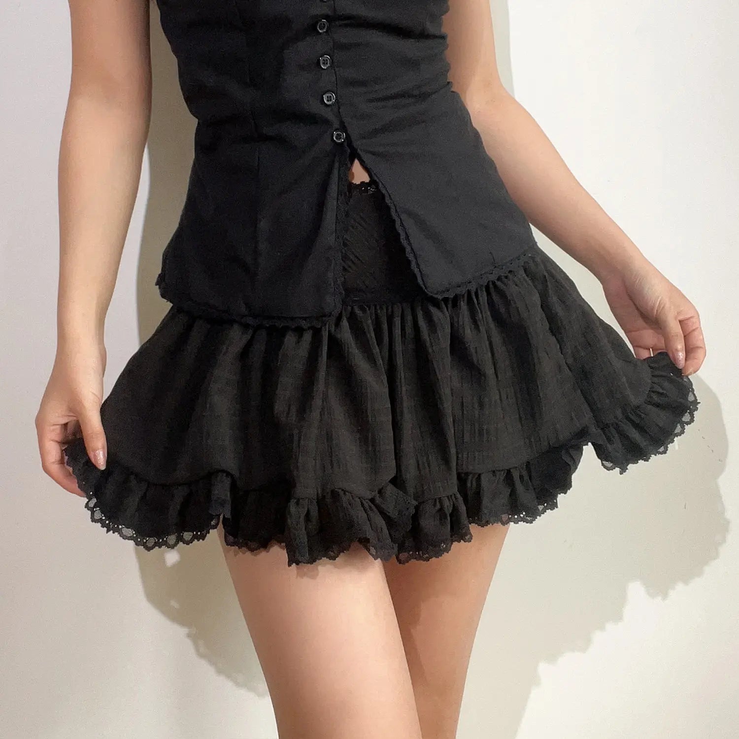 Black mini skirt hand hold hem detail shot, layered gathered textured fabric double eyelet lace hem fluffy drape fabric texture display