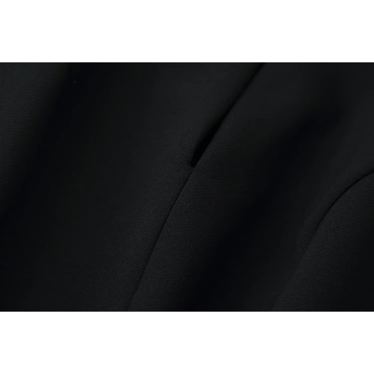 Close‑up fabric texture and vertical tailored seam of black mini dress