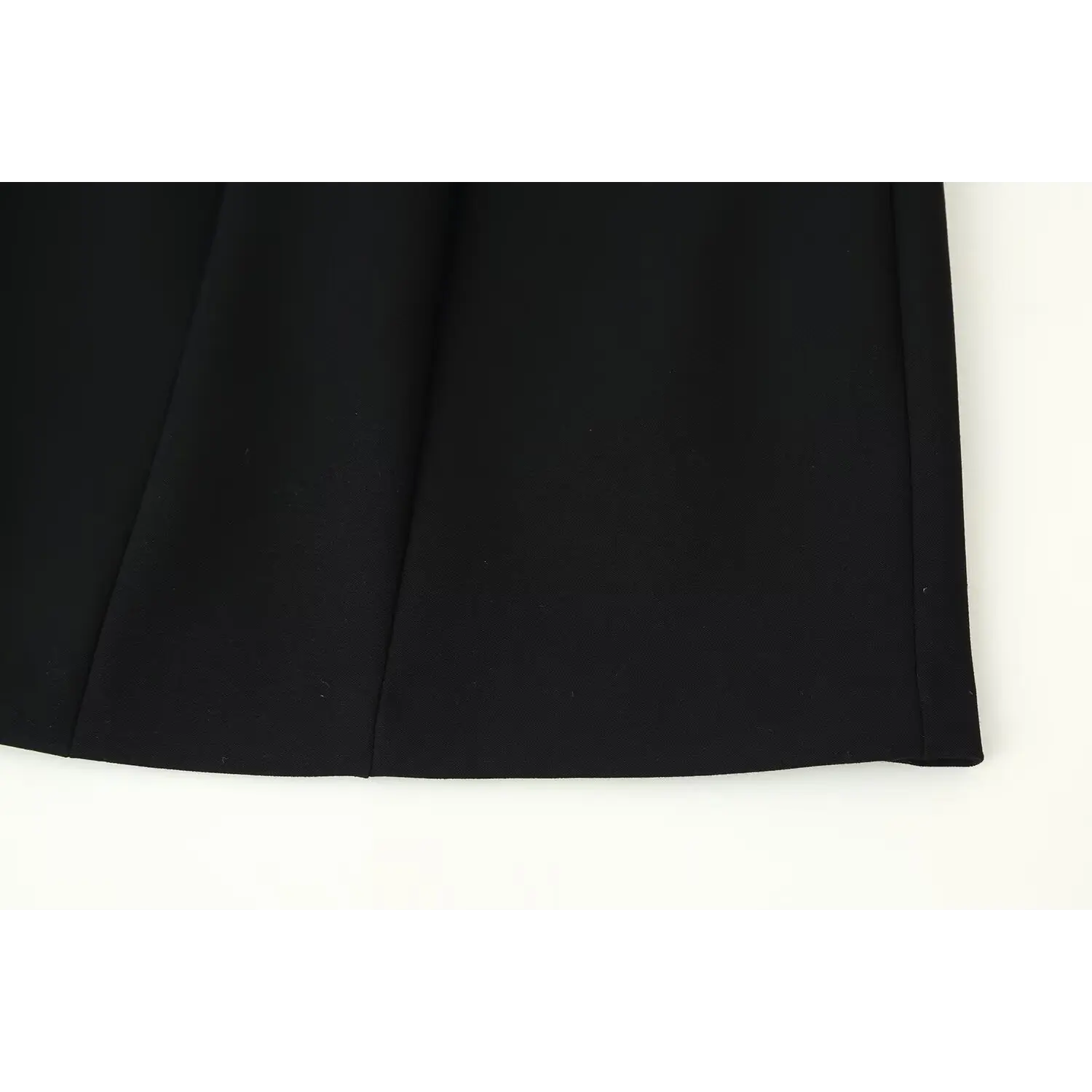 Close‑up finished bottom hem stitching of black tailored mini dress