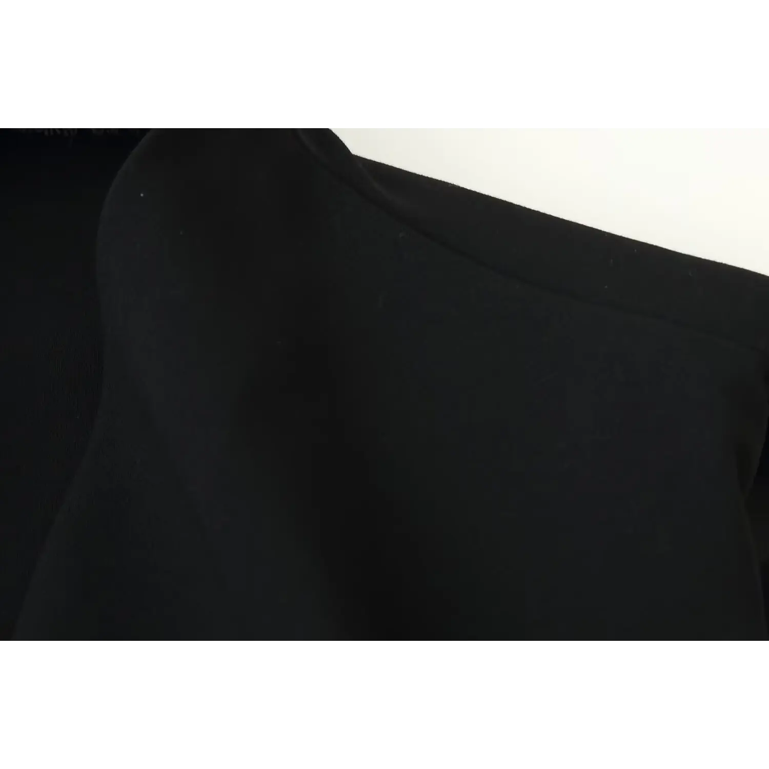 Close‑up shoulder seam stitching detail of black sleeveless mini dress