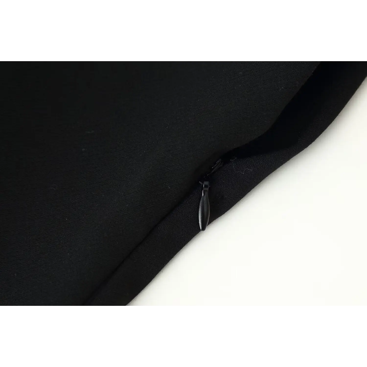 Close‑up invisible side zipper detail on black sleeveless mini dress