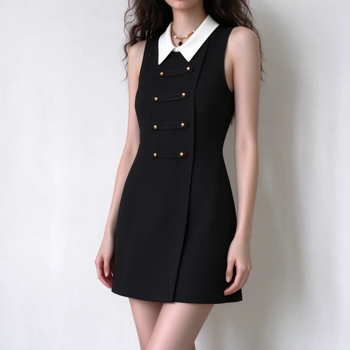 Female model wears black sleeveless mini dress with detachable white collar, four rows gold button decor, tailored slim fit, front full torso shot