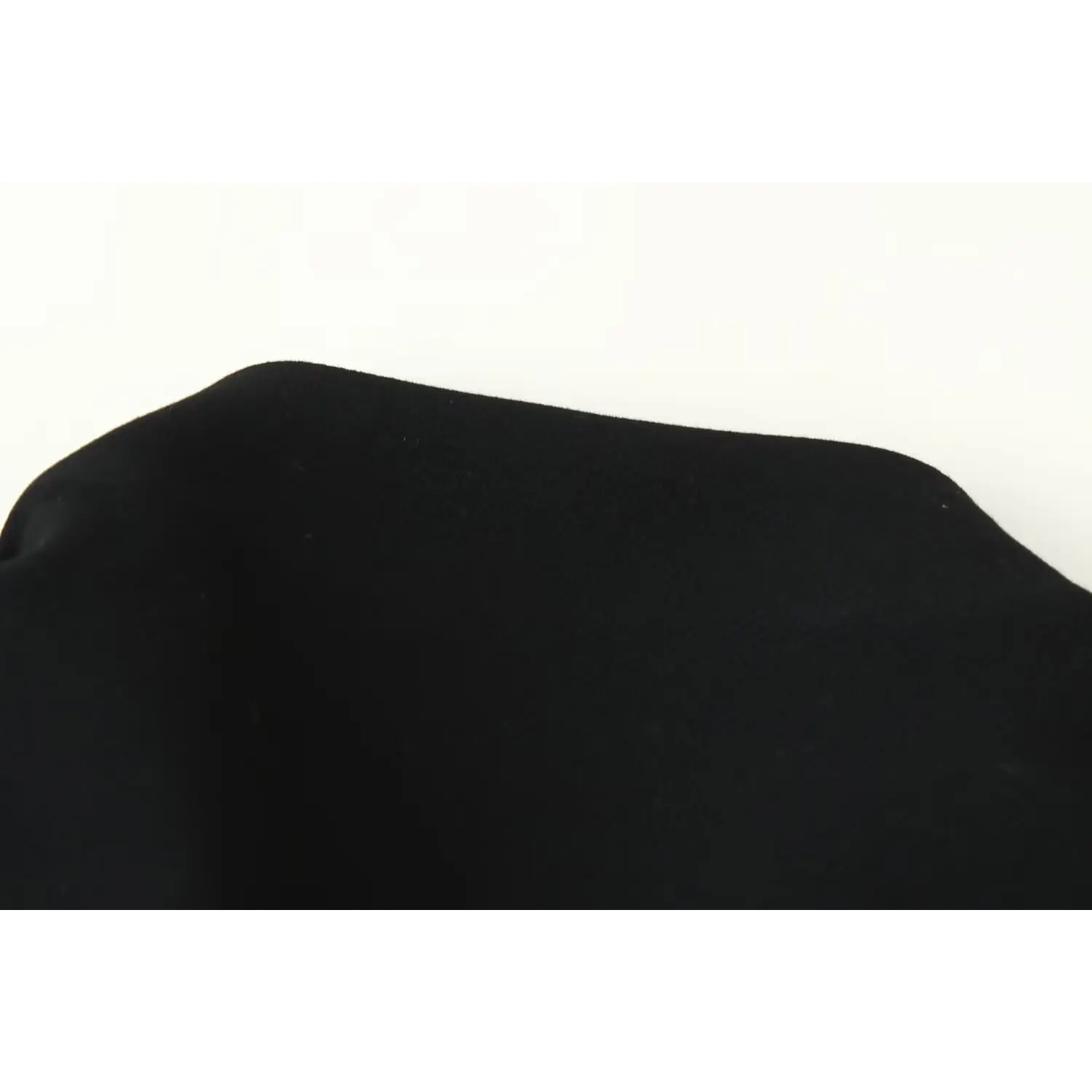 Close‑up view of black smooth woven suit dress fabric texture against off‑white background