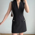 Model wearing black sleeveless v‑neck suit mini dress with decorative pocket buttons, front full view