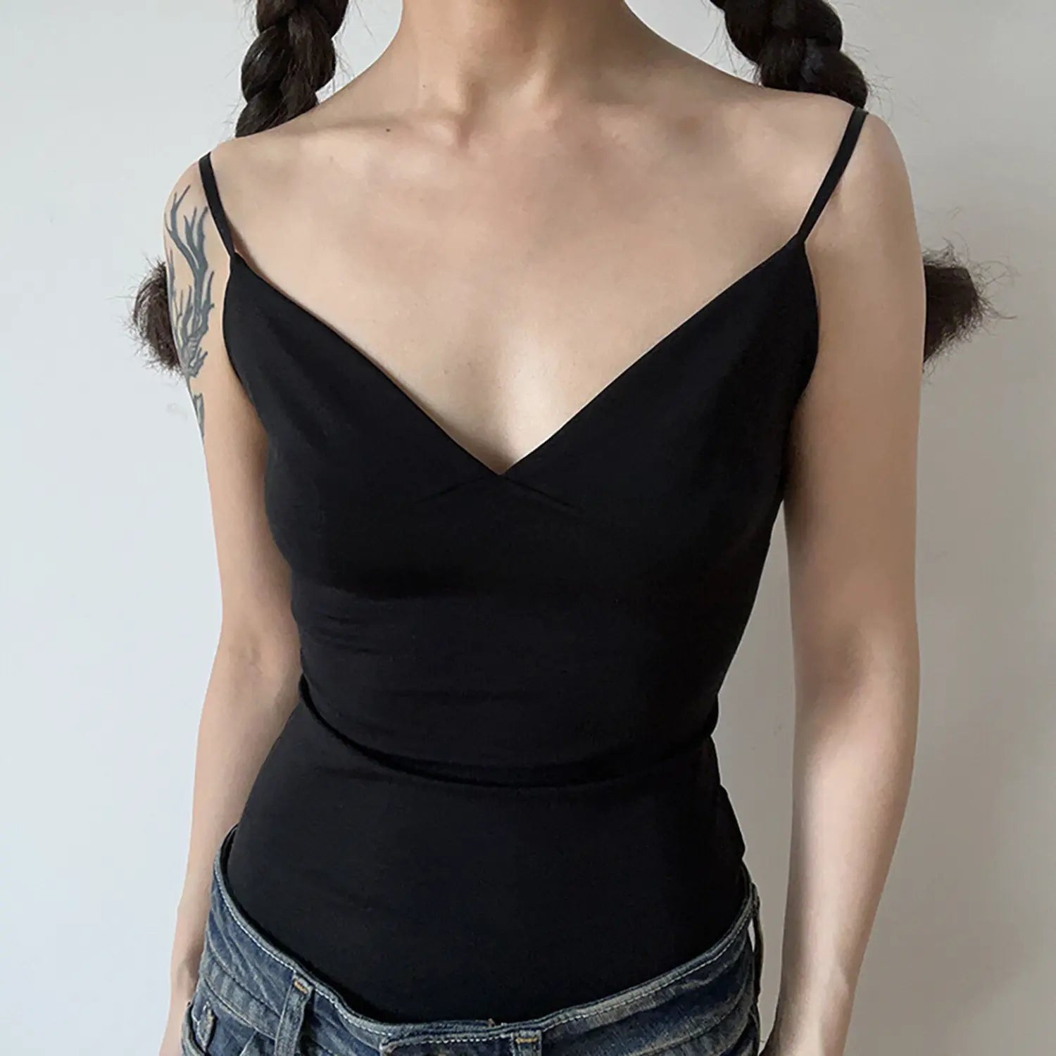 Close front view solid black smooth jersey cami tank top, deep wrap V neck slim bodycon silhouette thin spaghetti straps casual layering top