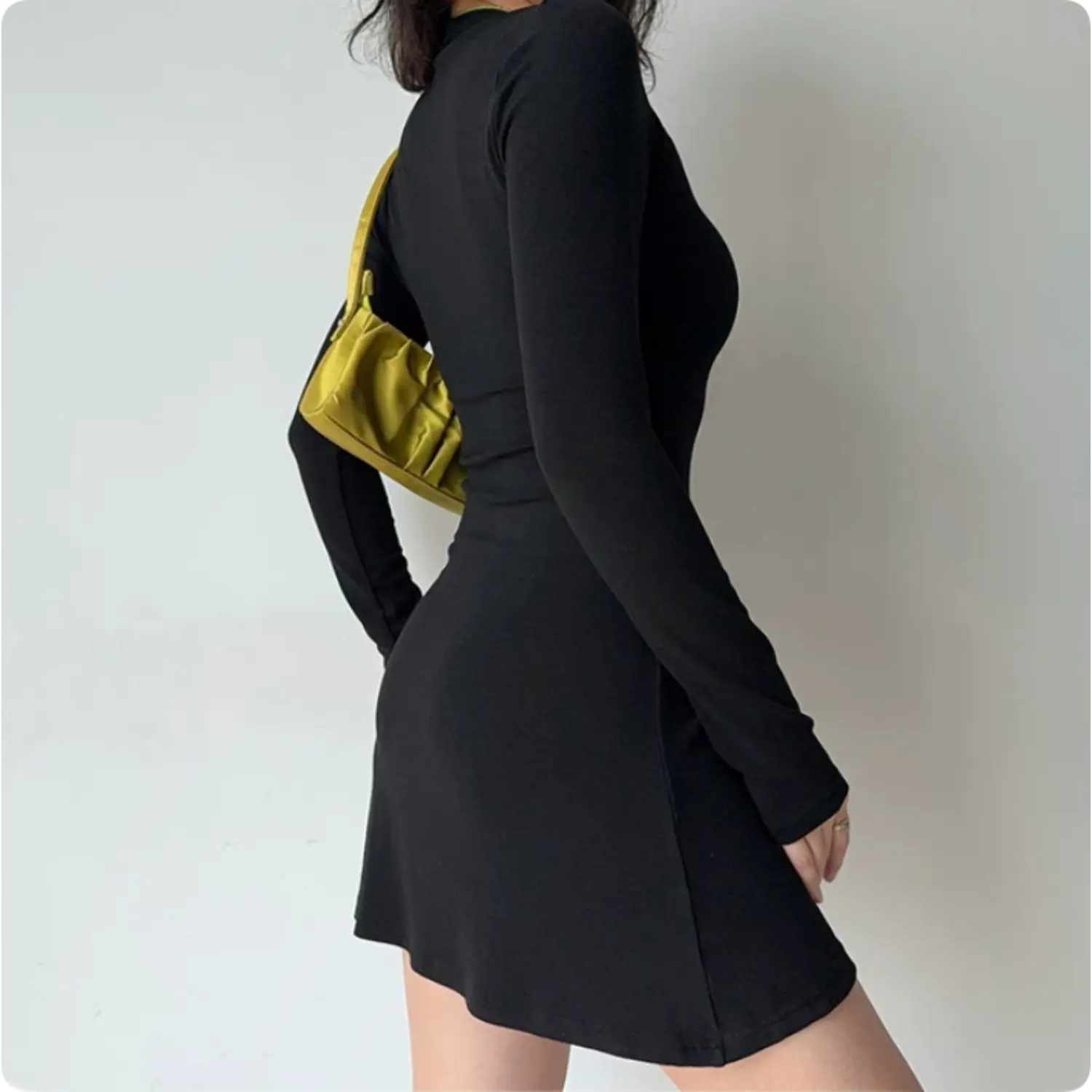 Back three‑quarter profile shot black square halter long sleeve mini dress showing back fit and skirt flare
