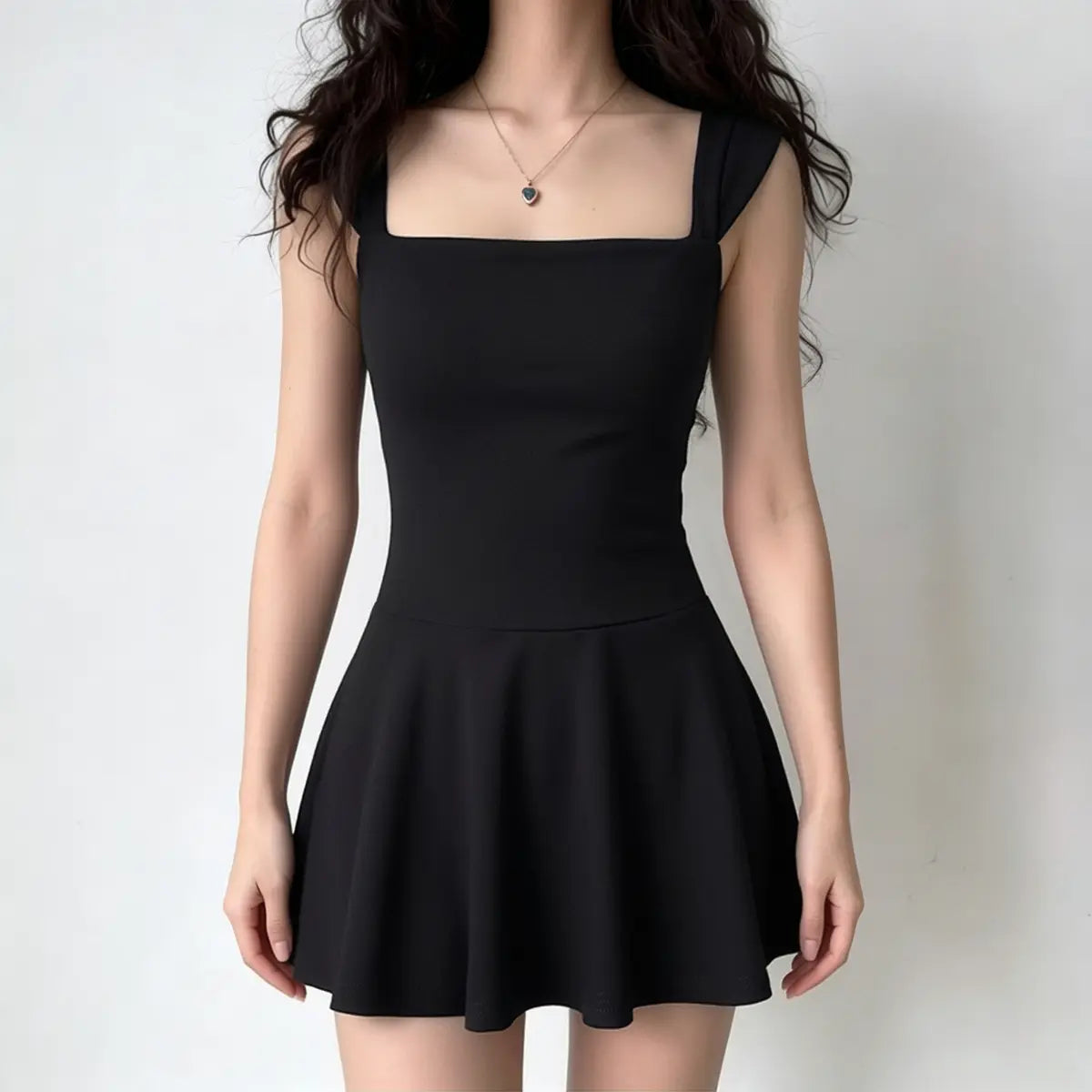 Full-body shot of a woman wearing a black sleeveless fit-and-flare mini dress with a square neckline.