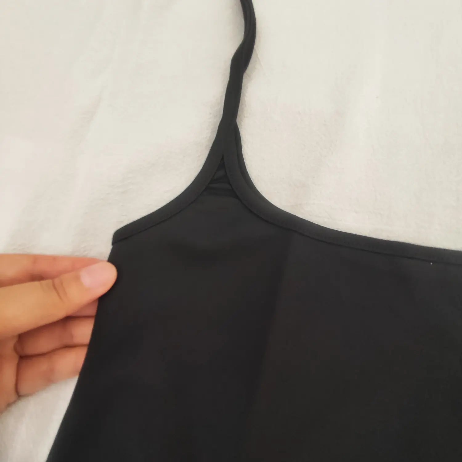 Close‑up shoulder strap and neckline seam detail of black tie suspender mini skirt
