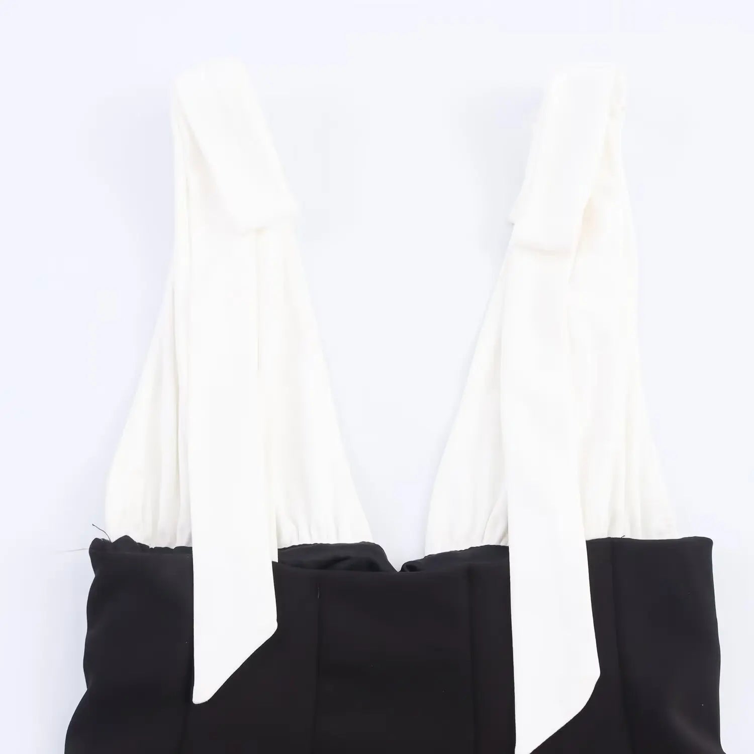 Close-up of bow-tie shoulder straps and gathered neckline on black and white fit-and-flare dress
