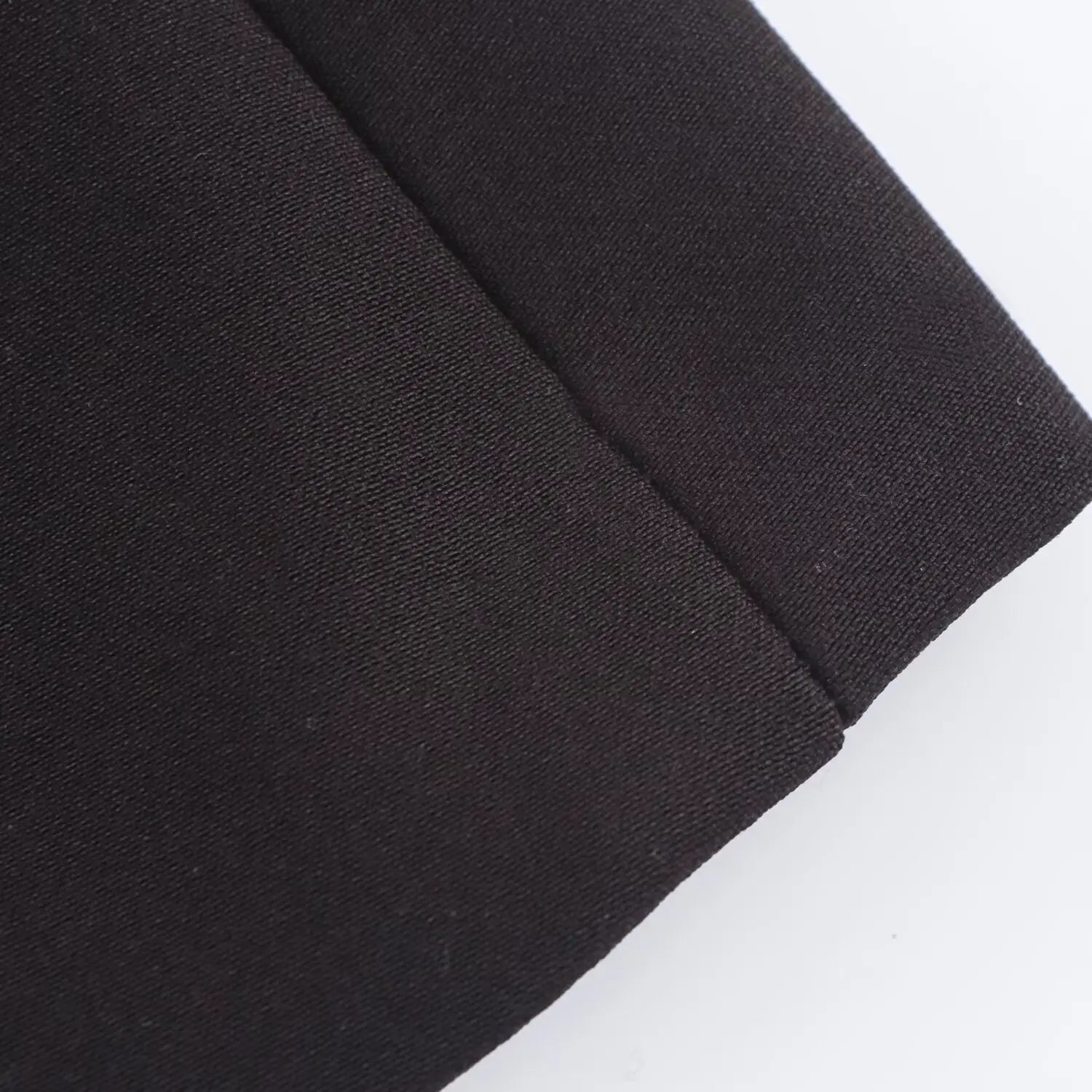 Close-up detail of the black woven fabric hem and seam on the fit-and-flare dress