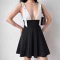 Lifestyle wearing shot of black and white bow-tie strap fit-and-flare mini dress, paired with accessories