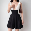 Front lifestyle shot on model of black white color block mini dress, bow detail shoulder straps, V neck bust, high waist flared skater skirt