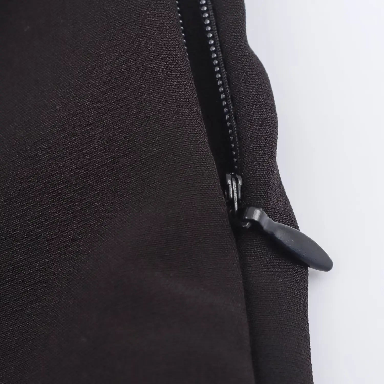 Close-up of the side zipper and its pull tab on the black and white dress
