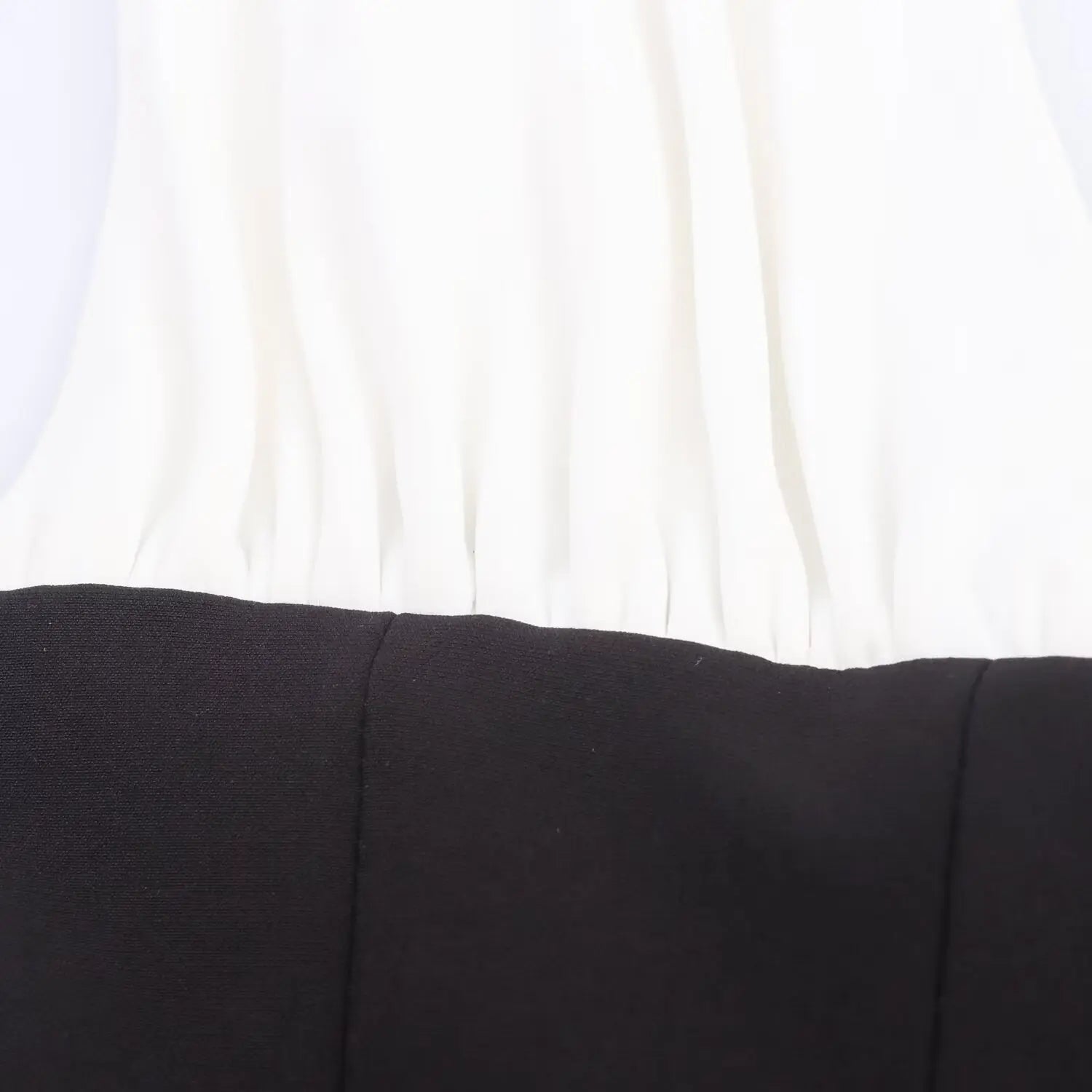 Close-up of seam detail at the waist where white straps meet black bodice fabric