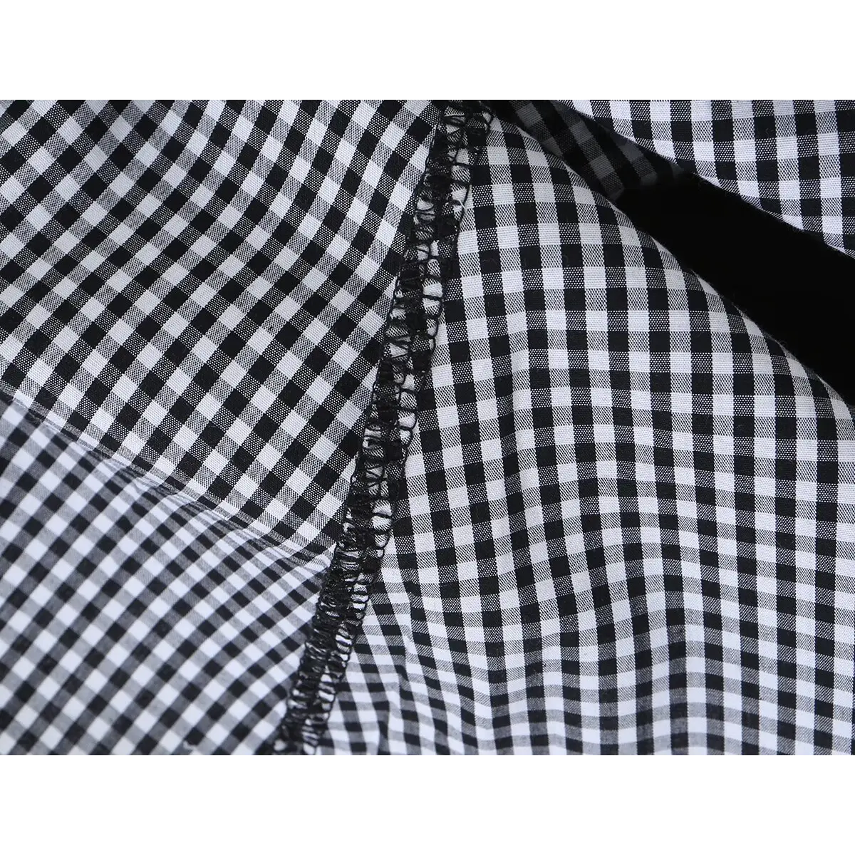 Close-up of the gathered waist and V-shaped seam detail on the gingham dress.