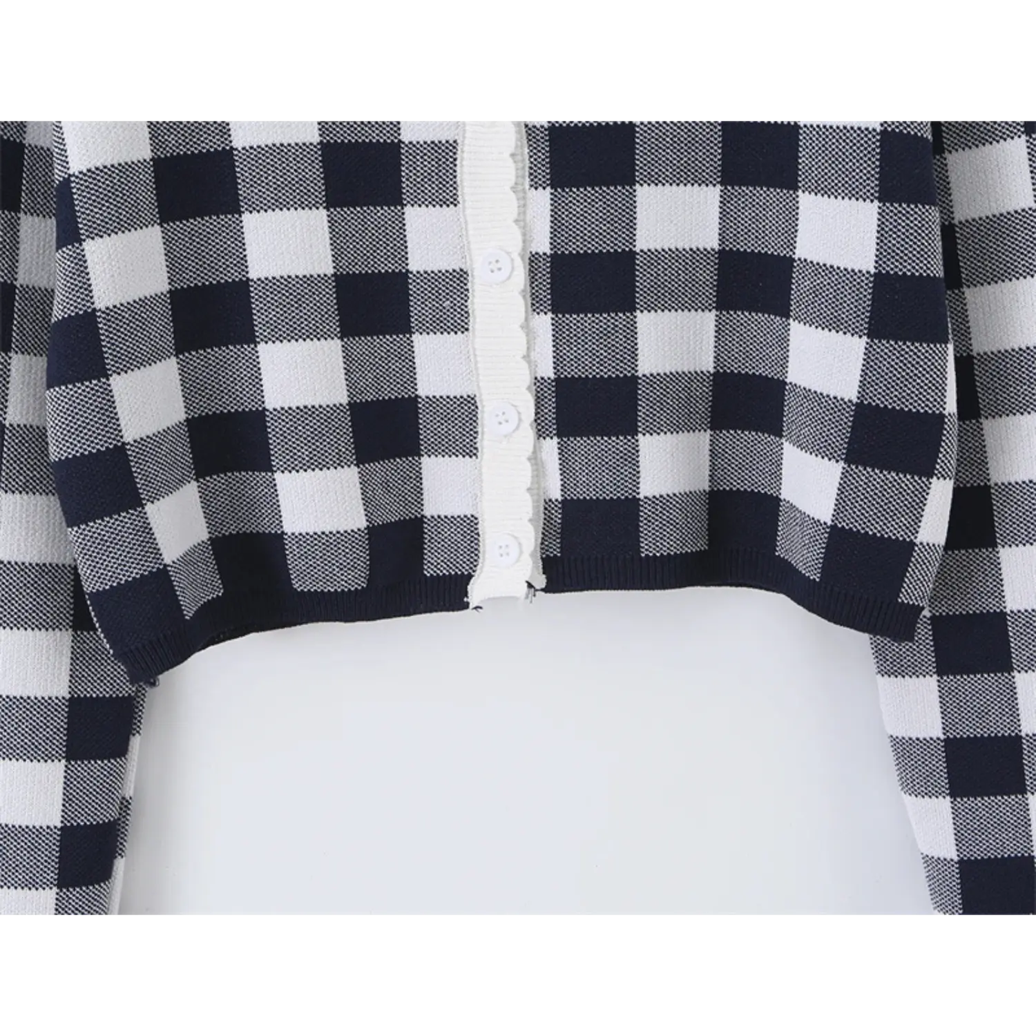 Bottom hem front placket macro shot, white round matching knit buttons, scalloped wave rib trim along opening edge, grid check knit texture