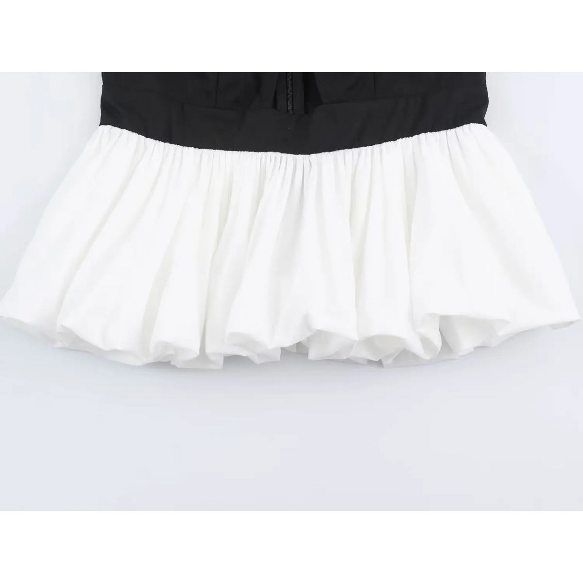 Close-up of black bodice meeting white pleated tulle hem on two tone top