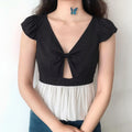 Model wearing black and white peplum top with blue jeans on white background