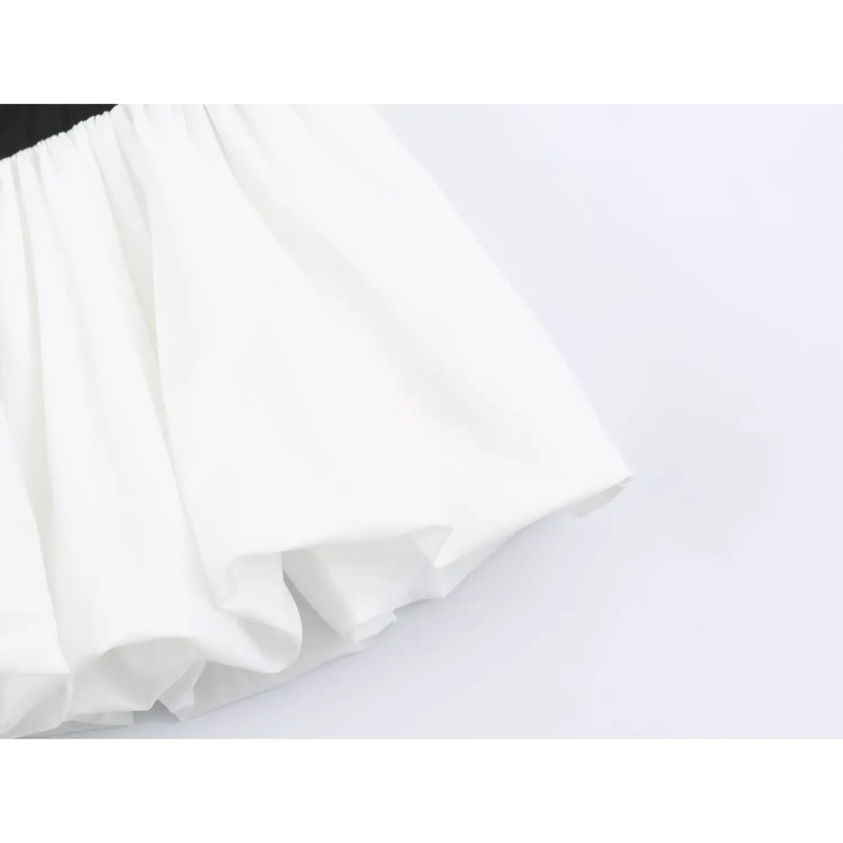 Close-up of black elastic waistband with white pleated puffy skirt hem