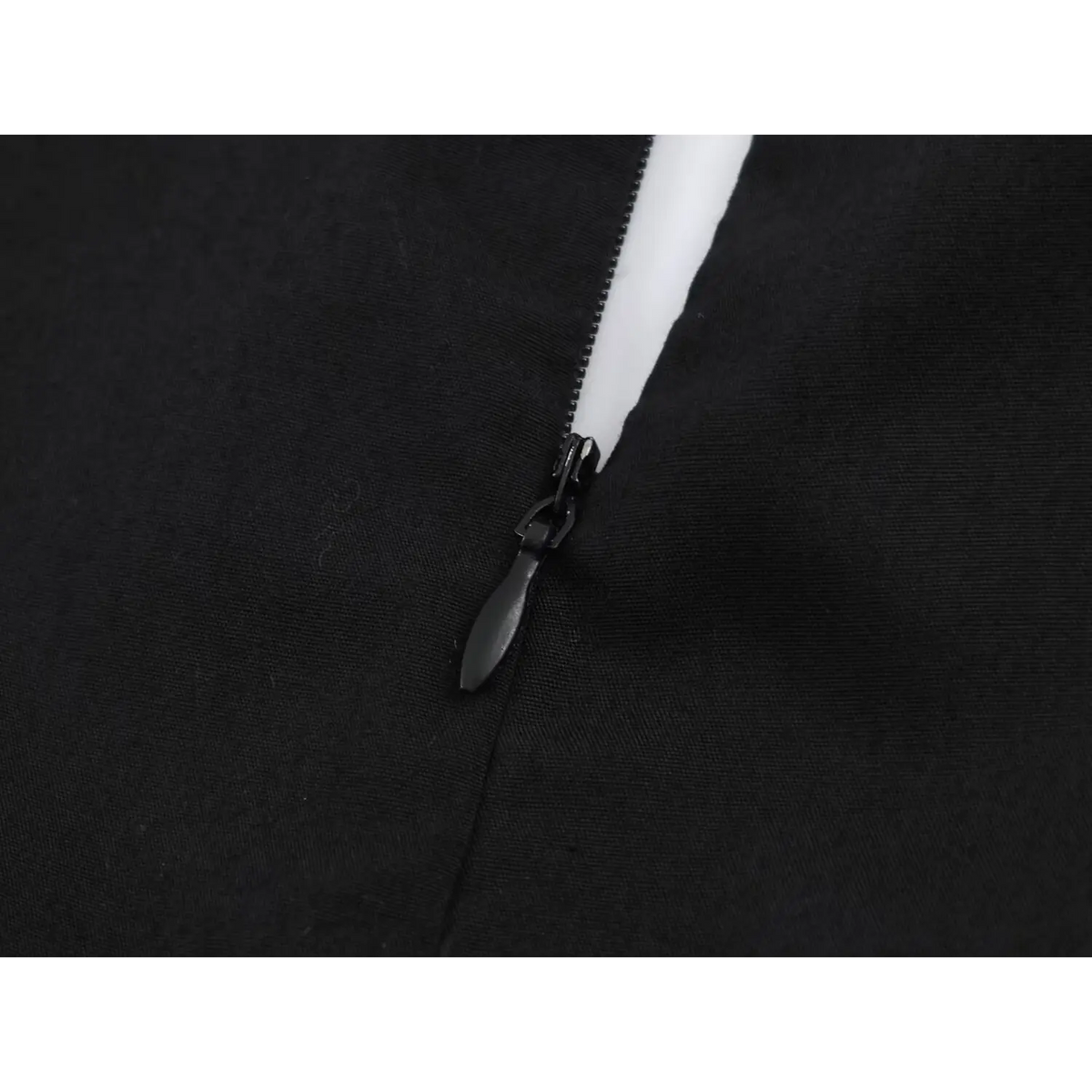 Close-up of black metal zipper with white lining on black fabric