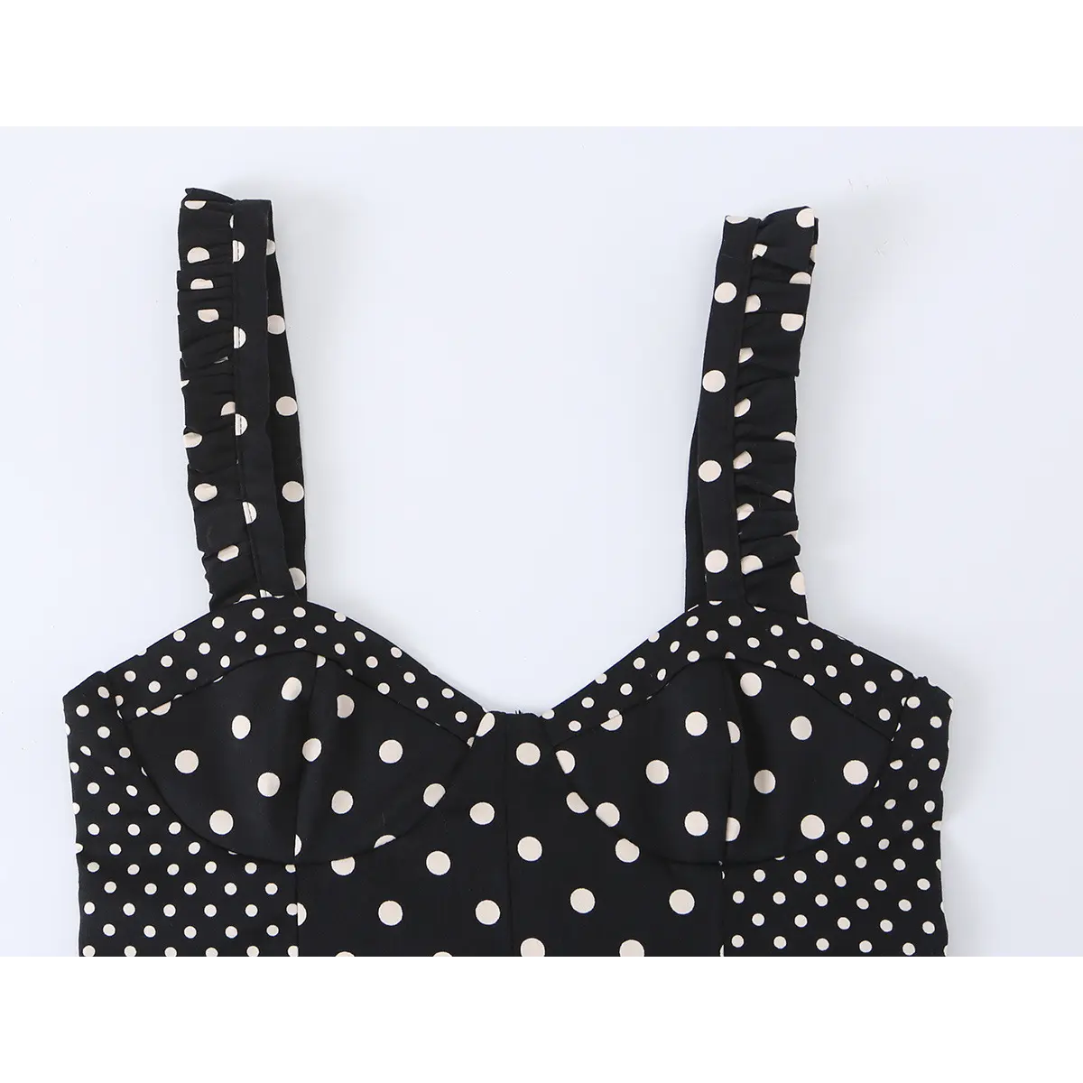  Close-up front view of a black and white polka dot bustier crop top, highlighting the sweetheart neckline and ruffled straps.