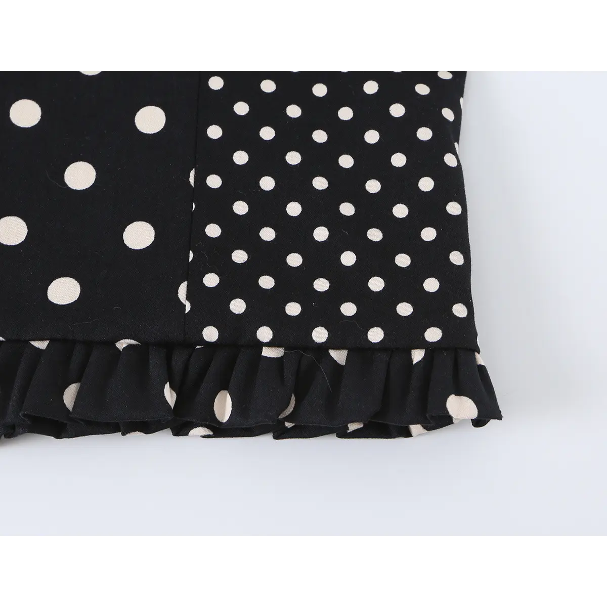 Close-up detail of the gathered ruffled hem on a black and white polka dot bustier crop top.