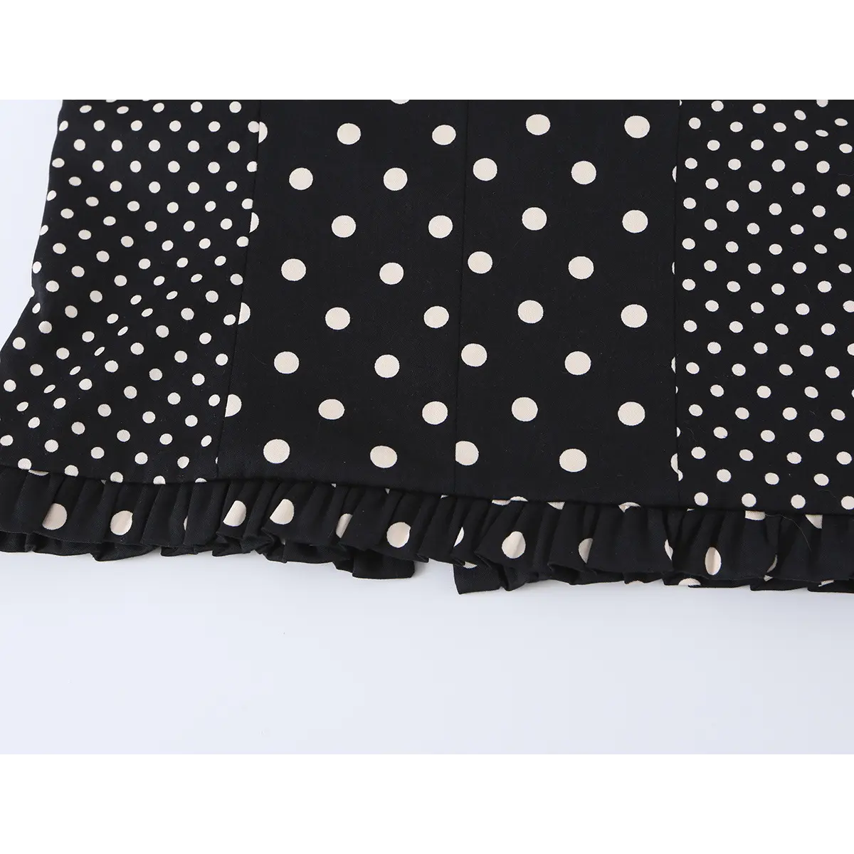 Close-up detail of the ruffled hem on a black and white polka dot bustier crop top, showing the fabric texture and pattern.