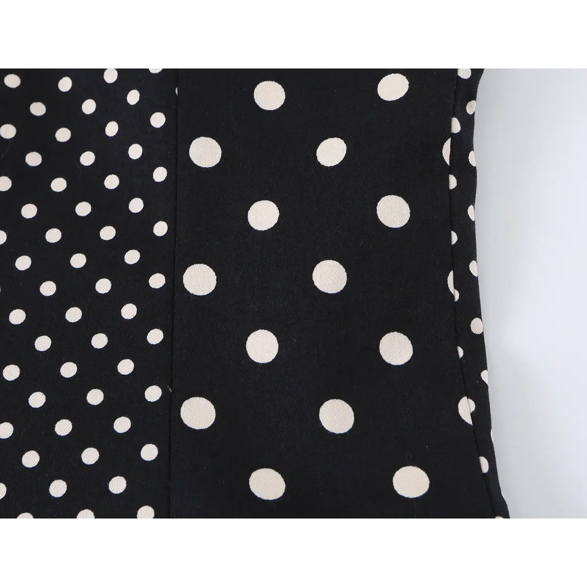 Close-up detail of the side seams and polka dot pattern on a black and white bustier crop top.