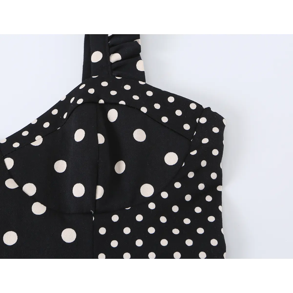 Close-up detail of the sweetheart neckline and ruffled strap construction on a black and white polka dot bustier crop top.