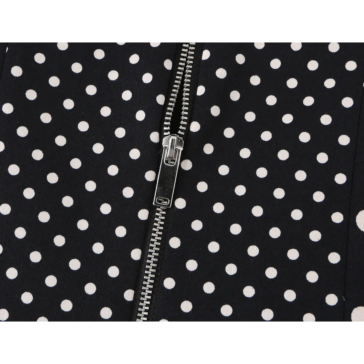 Close-up detail of the center-back metal zipper on a black and white polka dot bustier crop top.