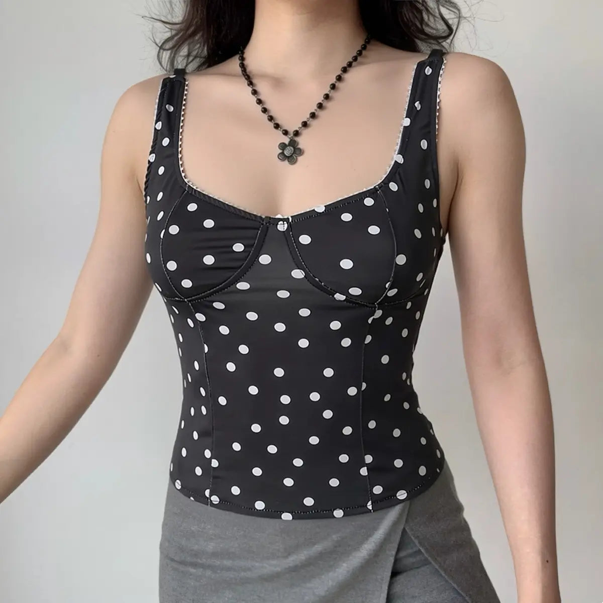 Woman wearing black polka dot cami top with sweetheart neckline, full front view