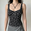 Model wearing a black and white polka dot corset-style camisole top with lace trim at the neckline, paired with a gray wrap skirt.