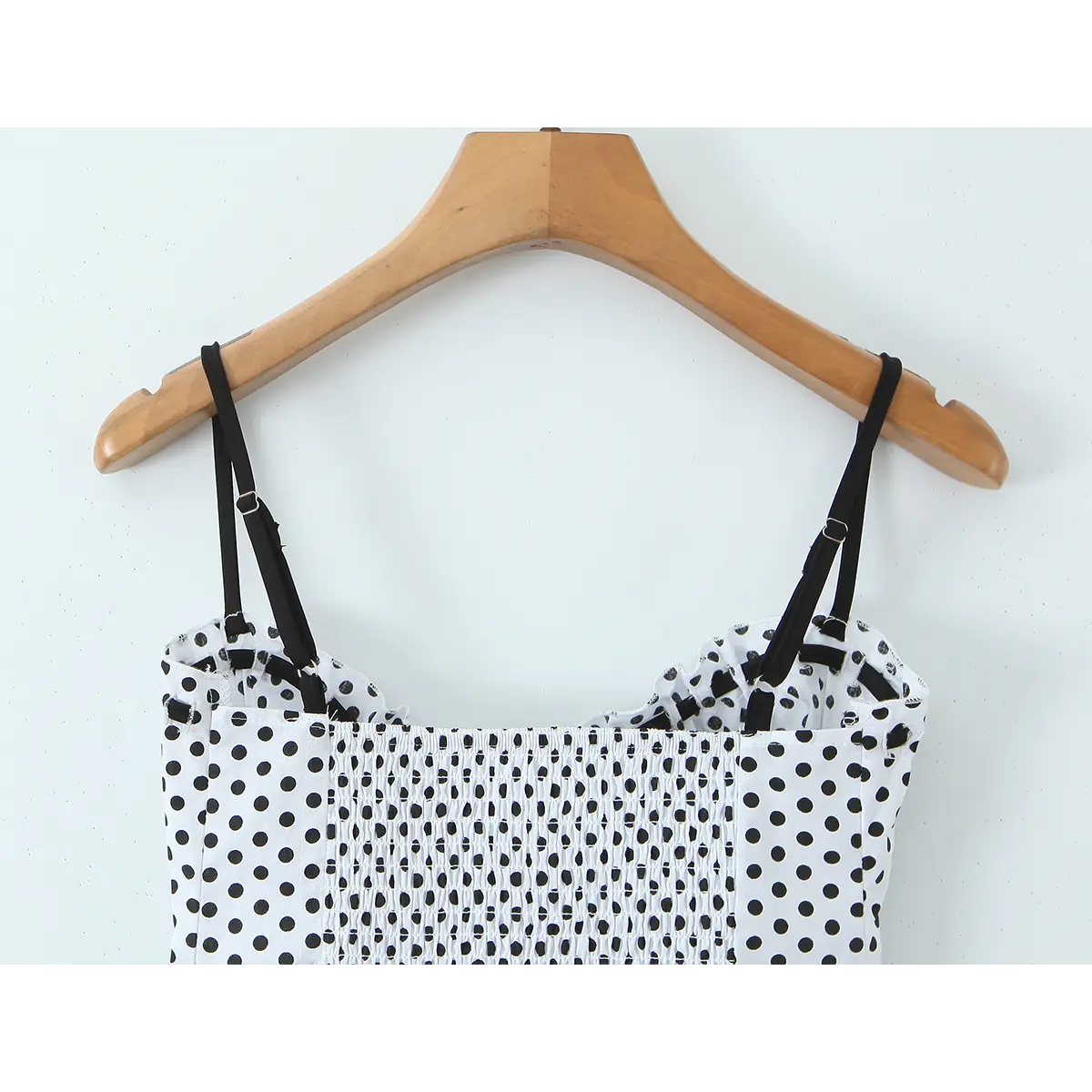 Front studio shot of the black and white polka dot camisole, showing the adjustable straps and smocked bust.