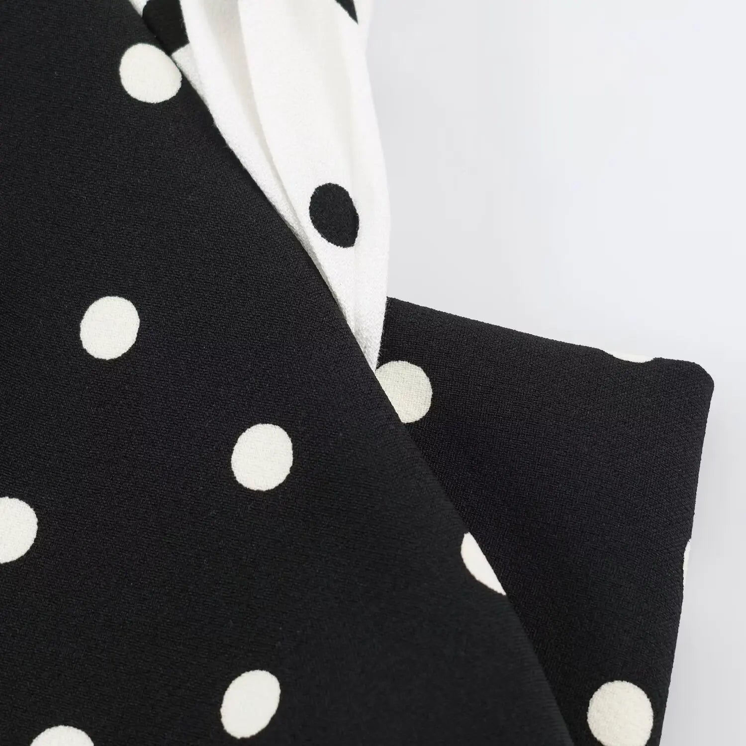 Close‑up fabric texture of black base with white polka dot print