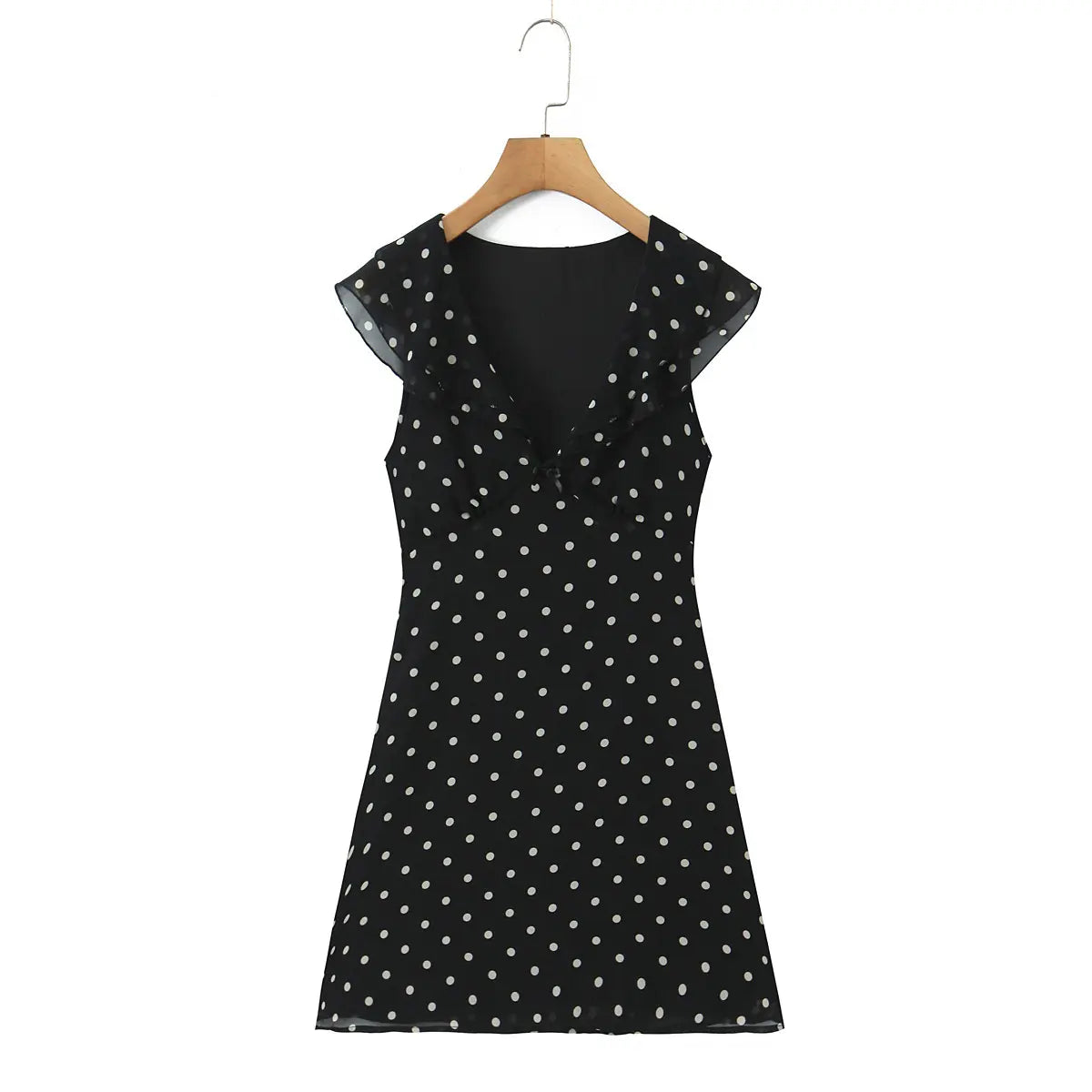 Full front view of the black polka dot dress with V-neck, ruffled trim, and waist bow.