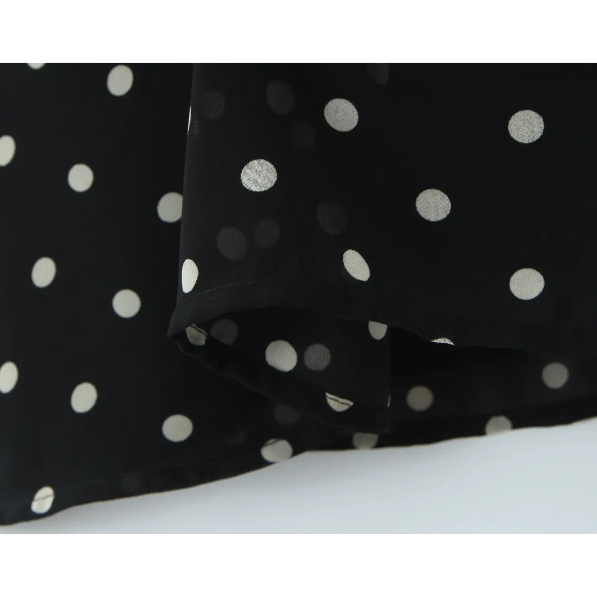 Close-up of the neatly finished hem on the black polka dot chiffon dress.