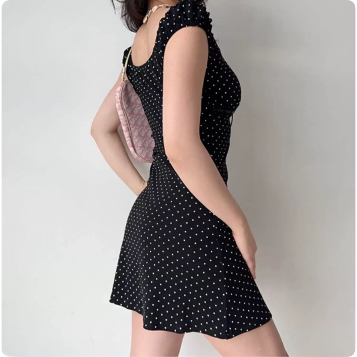 Model back three‑quarter view black white polka dot mini dress elastic puff cap sleeve fitted short dress