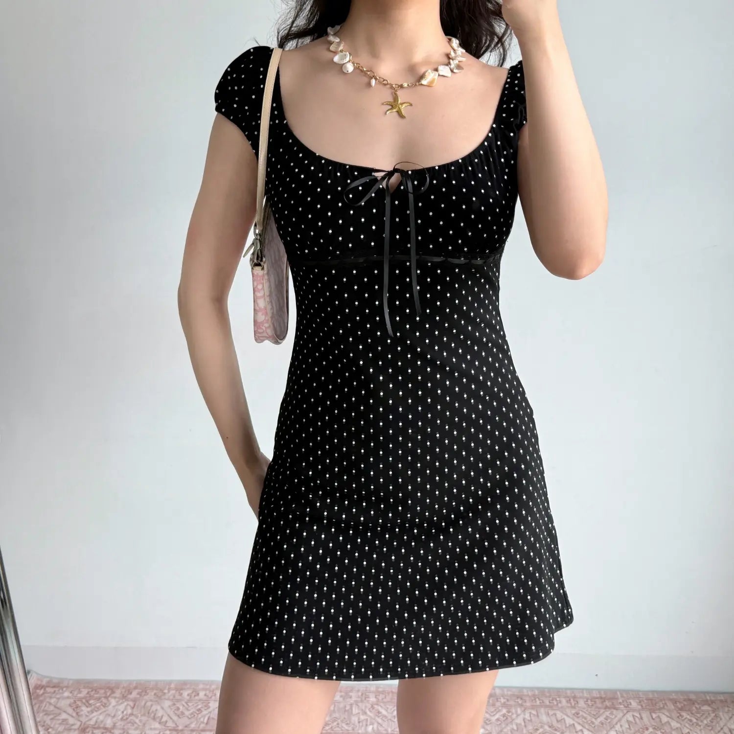 Model full front view black white polka dot mini dress square neck front ribbon tie lace trim cap puff sleeve bodycon short dress