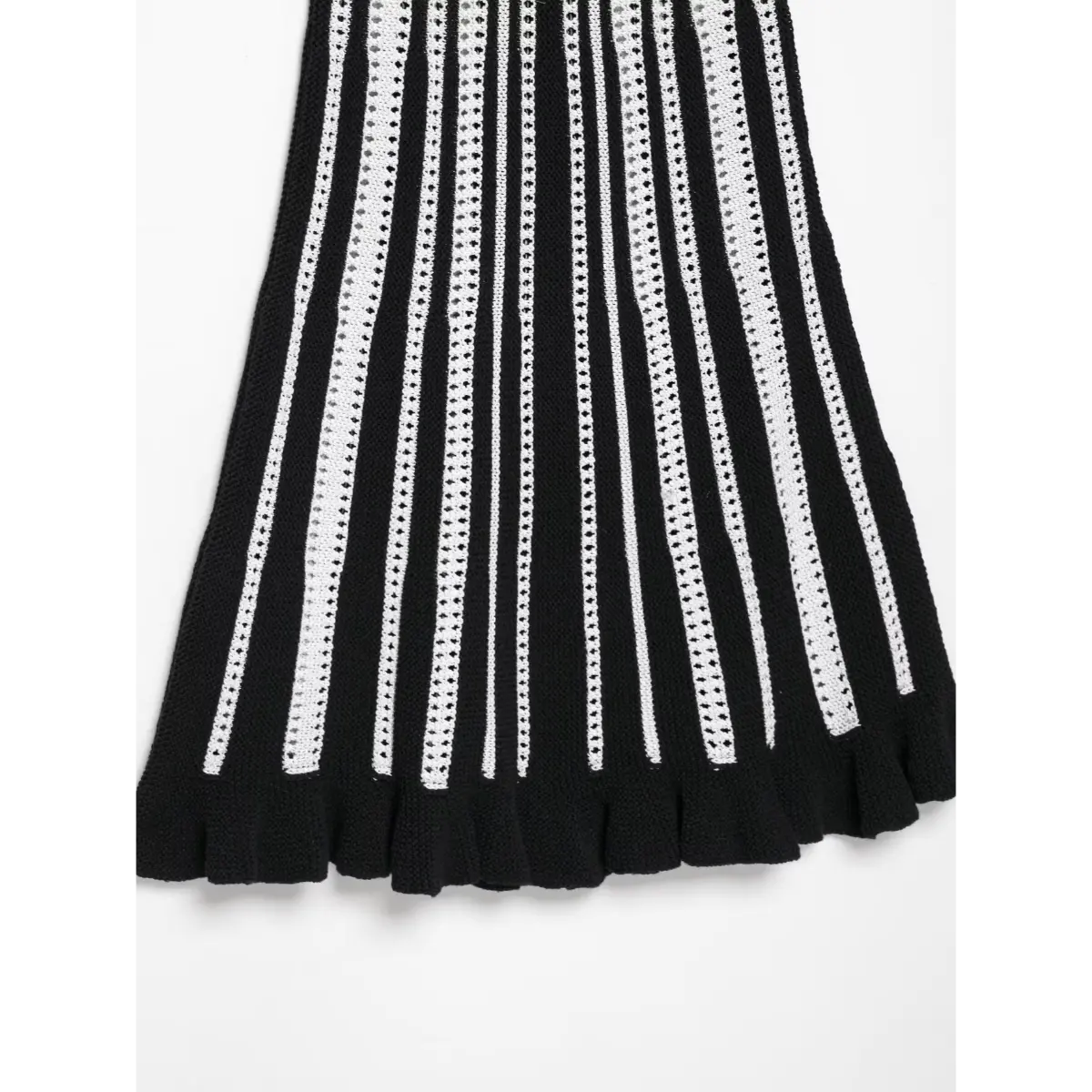  Close-up detail shot of the ruffled hem on a black and white striped knit mini dress, highlighting the flared knit trim.