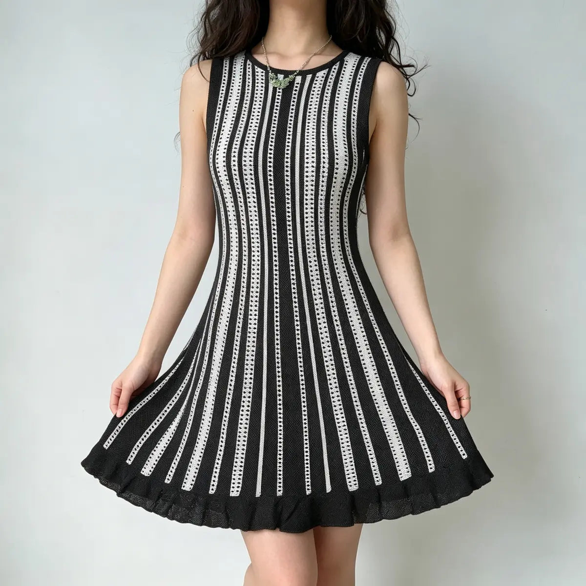 Model wearing a black and white striped knit mini dress with a ruffled hem, spreading the skirt to show the flared silhouette.