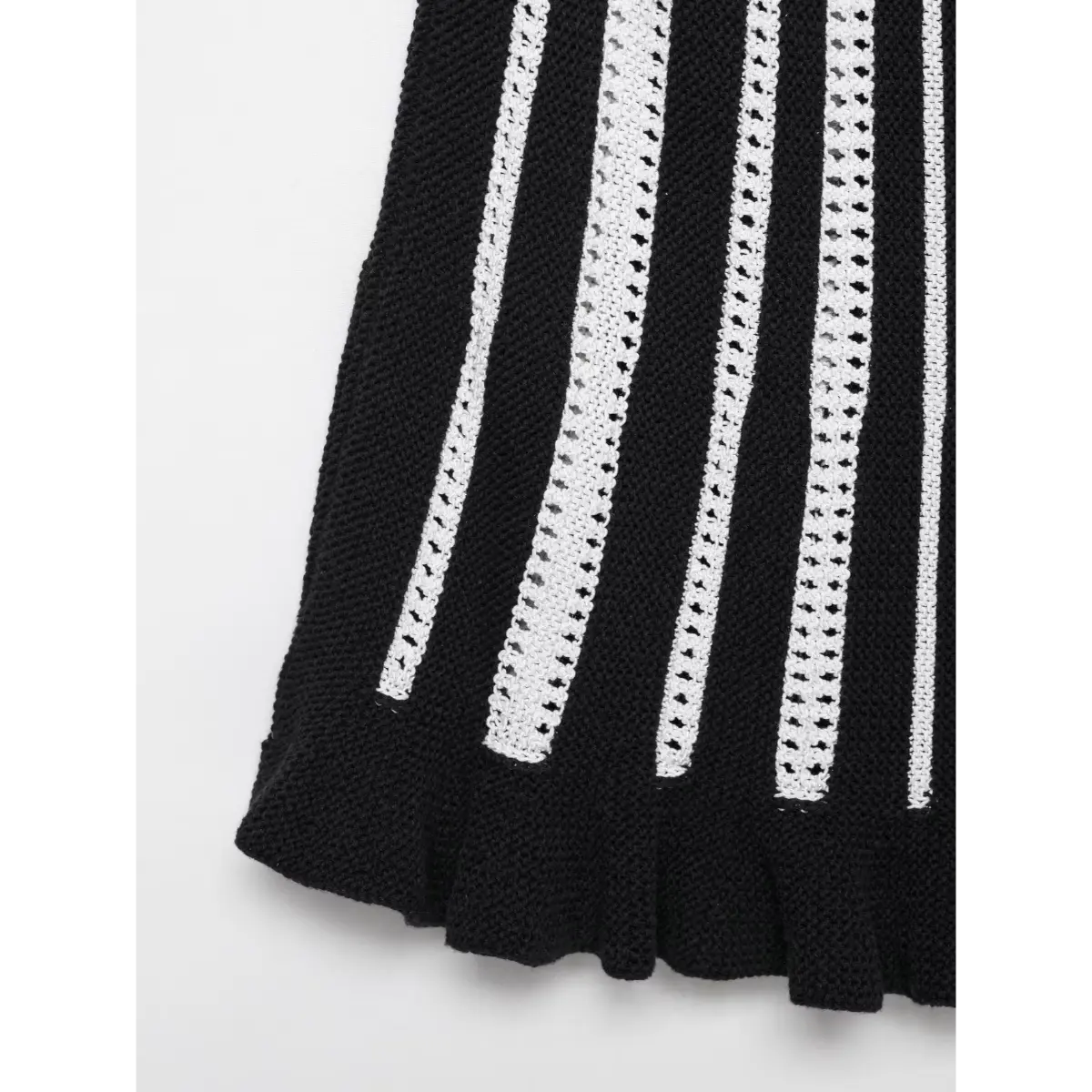 Close-up view of the skirt portion of a black and white striped knit mini dress, showing the alternating solid and openwork vertical stripes.