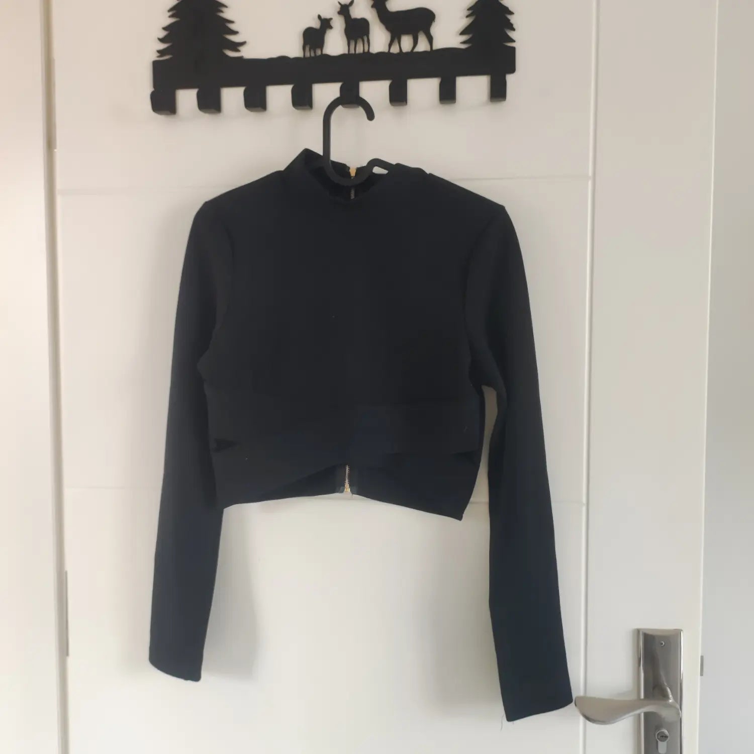 Black crossover cutout crop top hanging on hanger front view