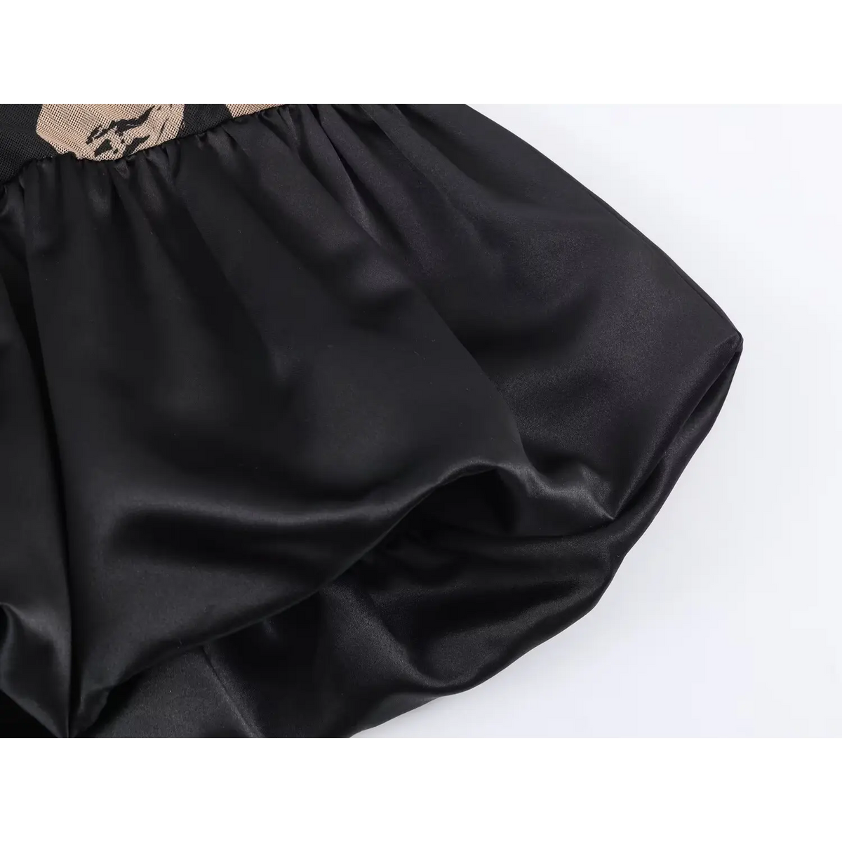 Close‑up view of gathered black satin ruffle hem for black floral mesh mini dress