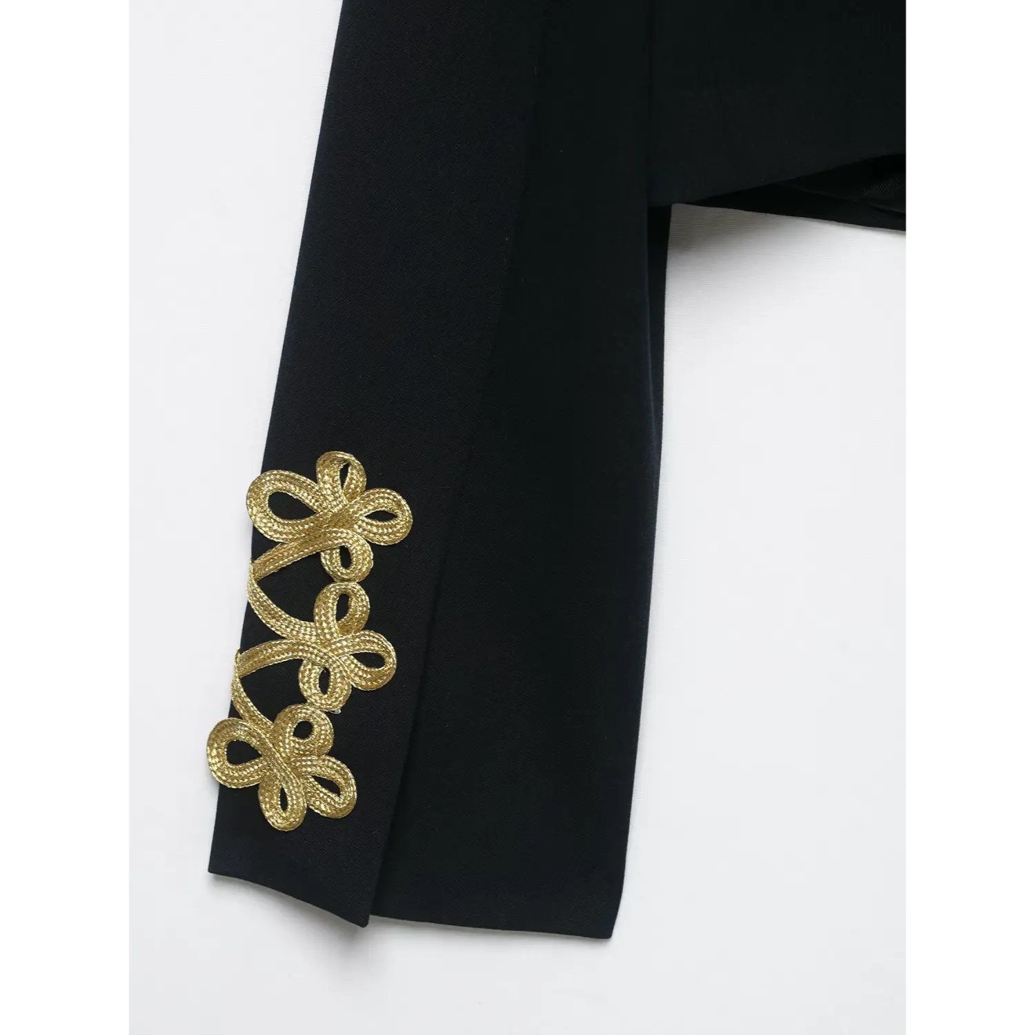 Close‑up of sleeve cuff gold braid embroidery detail on black cropped military blazer