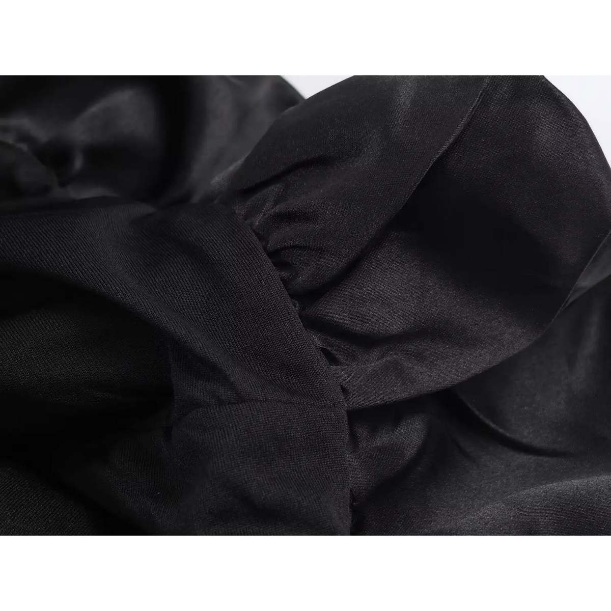 Macro shot of black satin fabric texture and stitching detail on dress hem