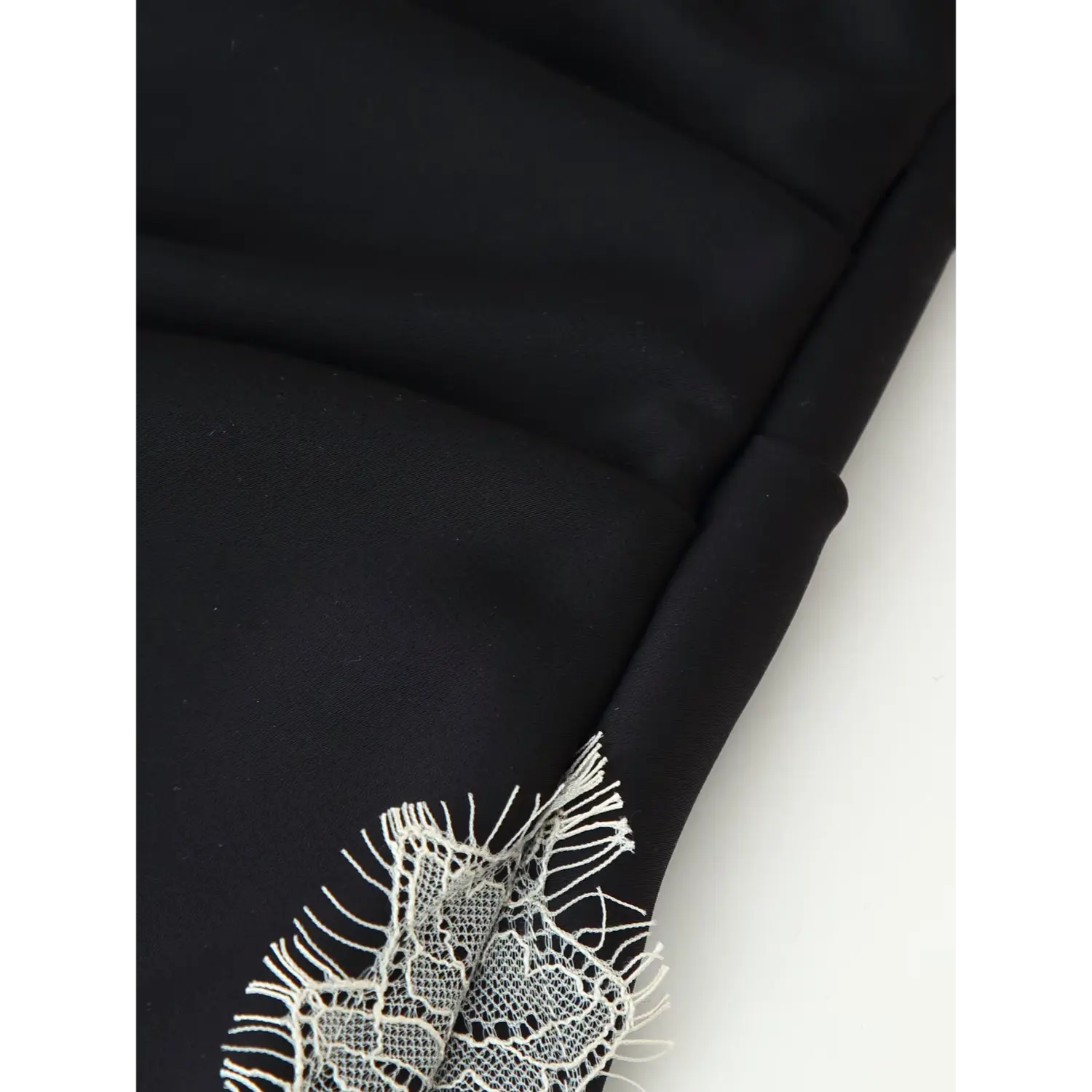 Close‑up of ruched black satin skirt, raw‑edge scalloped cream lace trim seam detail