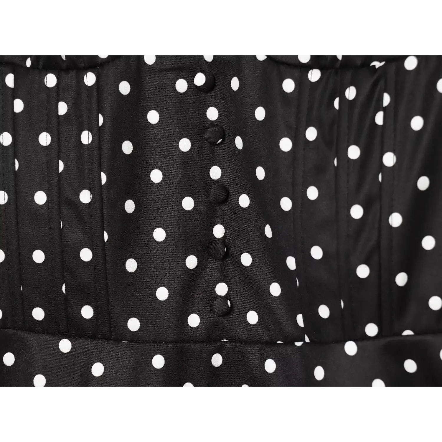 Black white polka dot dress bodice close‑up,fabric covered decorative buttons,pleated waist stitching